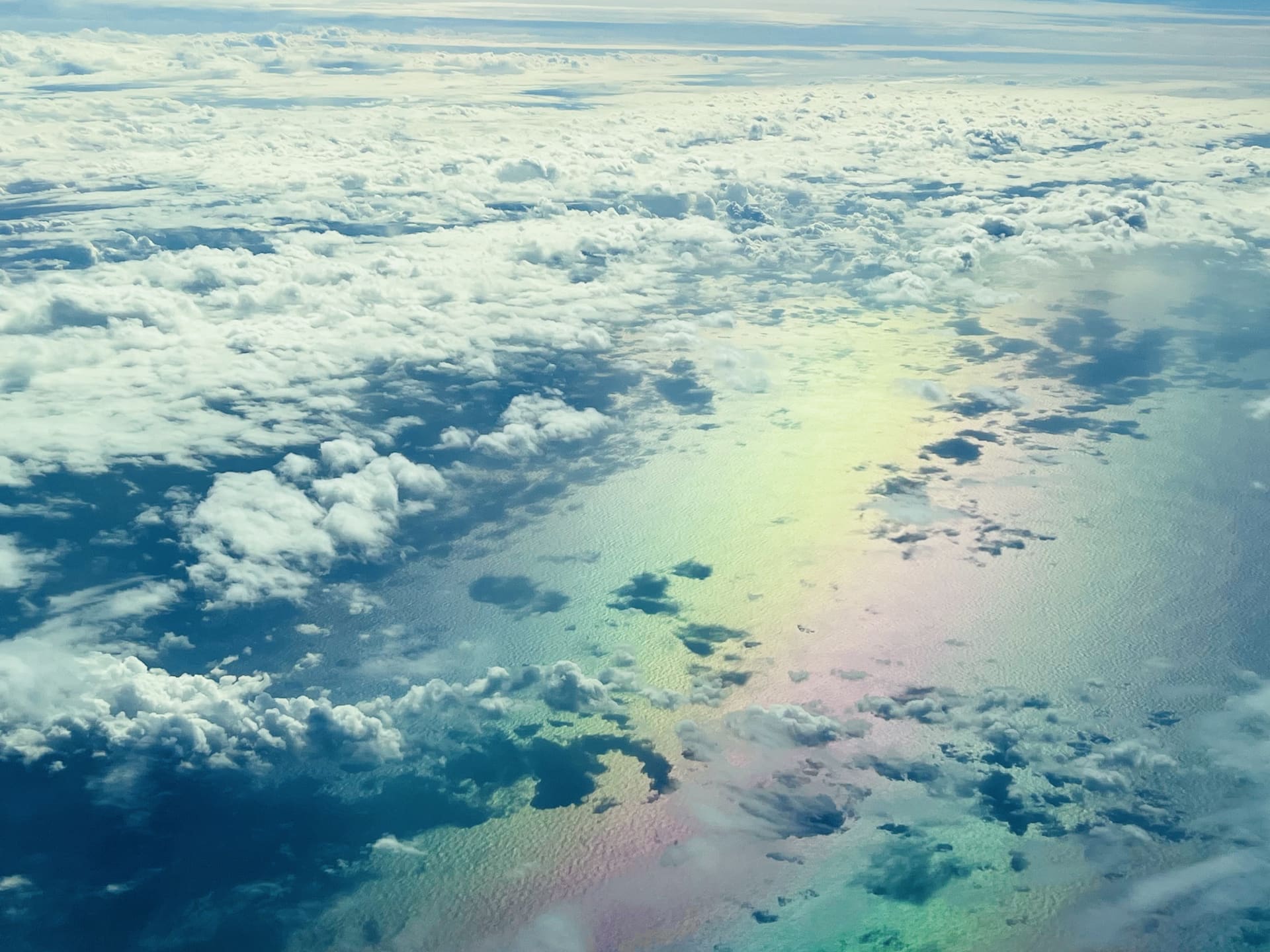 View of clouds and a rainbow-like glory from an airplane window